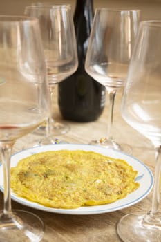 omelette with aromatic herbs and in the background goblets and bottle of wine