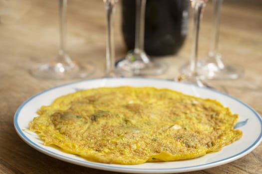 omelette with aromatic herbs and in the background goblets and bottle of wine