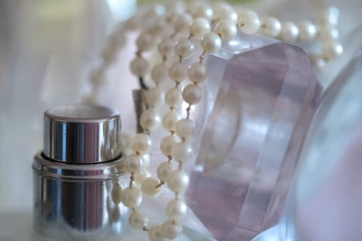 pearl necklace resting on perfume bottles