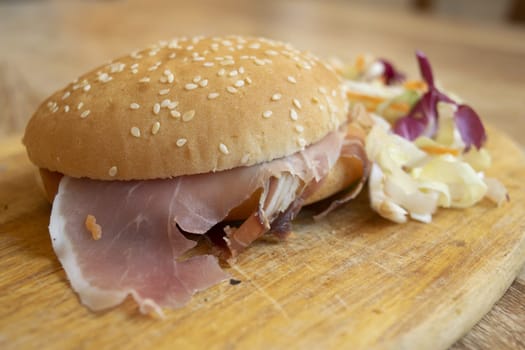 round sandwich filled with salad and raw ham