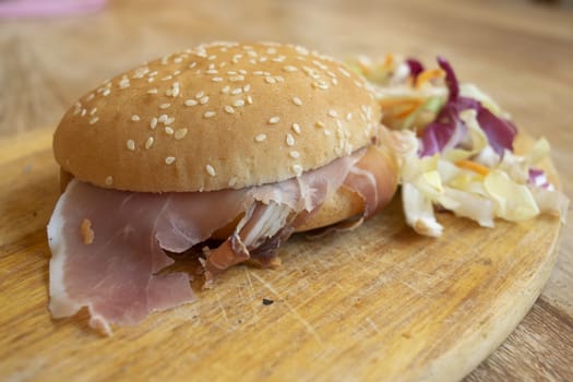 round sandwich filled with salad and raw ham