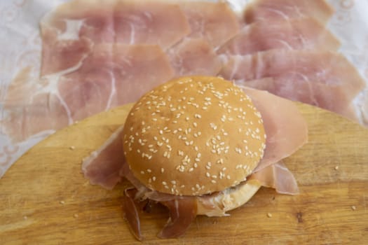 round sandwich with sesame seeds filled with raw ham