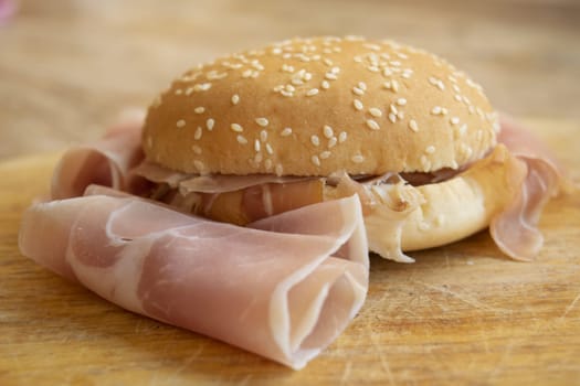 round sandwich with sesame seeds filled with raw ham