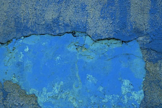 Cracked plaster on the wall. Abstract background from an old abandoned wall with blue plaster.