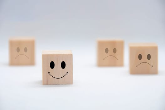 Happy and sad emoticon faces on wooden cubes with white background cover. Customer satisfaction and evaluation concept