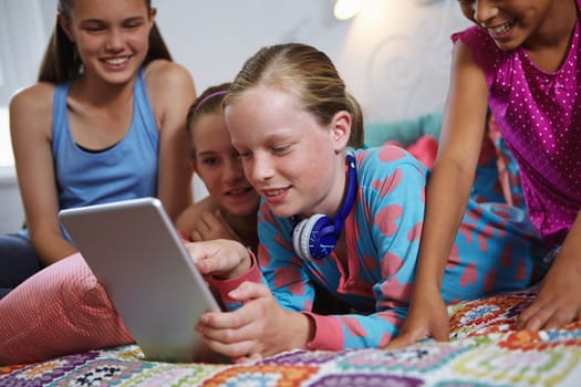 Movies are the best part of sleepovers. a group of teenage friends using a digital tablet together