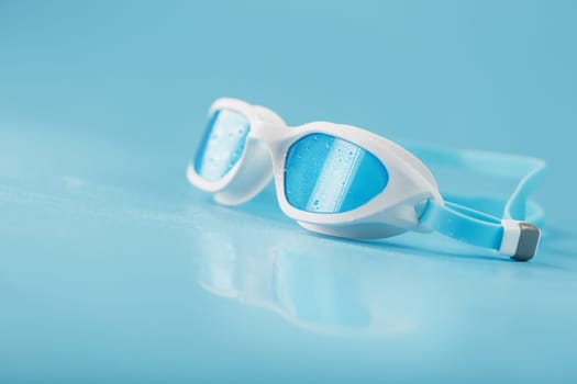 White swimming goggles on a blue background in a minimalist style with free space