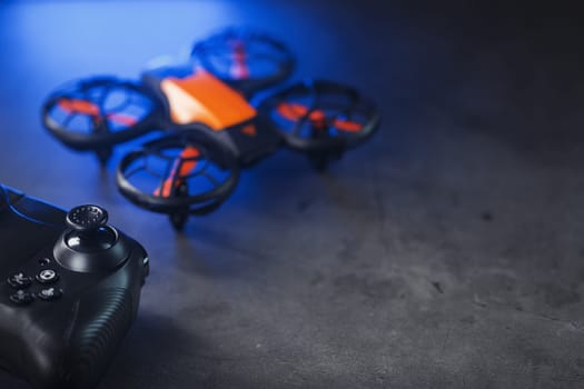 Gaming orange mini drone on a dark background for control from a gamepad