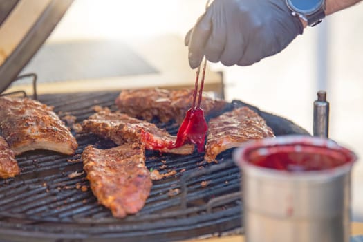 The process of grilling ribs. A man putting hot sauce on a piece of rib. Tis the season for barbecues and grilling. High quality photo