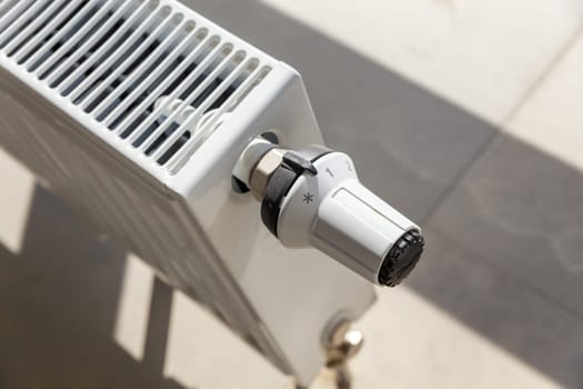 Close-up of white central heating floor radiator with a power regulator in the minimum position.