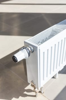 Close-up of white central heating floor radiator with a power regulator in the maximum position.