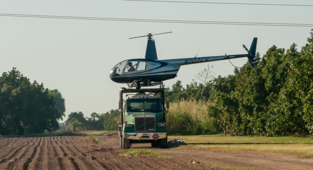 USA, FLORIDA - NOVEMBER 30, 2011: An agricultural helicopter on top of a large car in a field, Florida