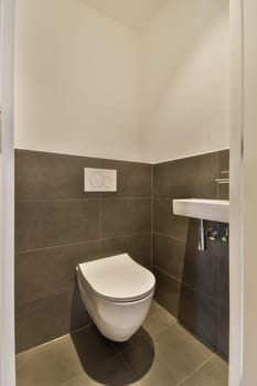 a toilet in the corner of a bathroom with grey tiles on the walls, and white trim around the toilet bowl