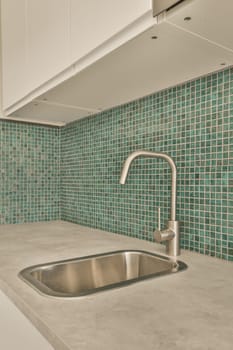 a kitchen with green tiles on the backs and white cabinets in the photo is taken from above, showing the sink