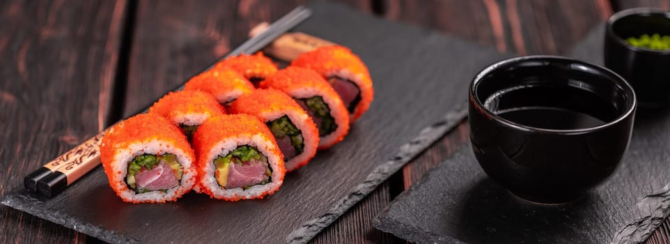 California sushi roll with crab, avocado, cucumber and tobiko caviar served on black board - Japanese food.