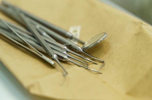 Dental instruments lie on wrapping paper before use. Close-up