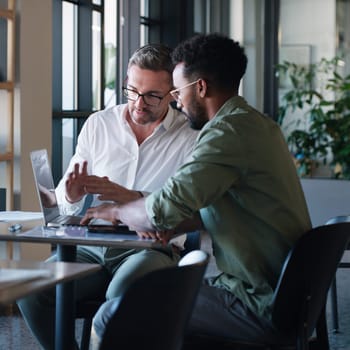 With teamwork, theyre well on their way to success. two businessmen using a laptop and having a discussion in a modern office