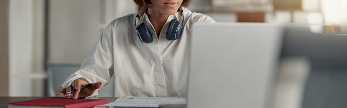 Business woman working laptop and making notes while sitting in modern office. Blurred background