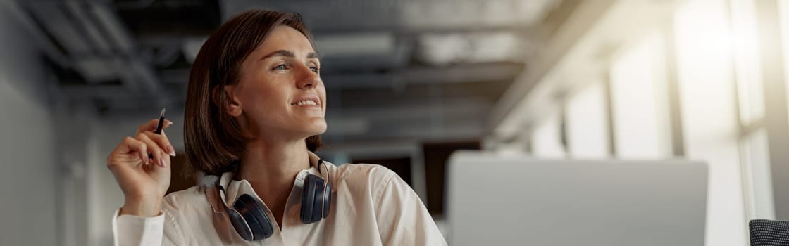 Business woman working laptop and making notes while sitting in modern office. Blurred background