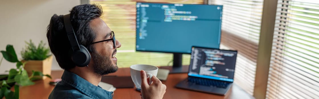 Man in headphones freelance data scientist work remotely at home while drink coffee