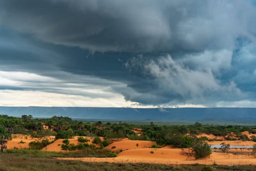 Stunning landscape with a vast expanse of sand dunes, open plains, and dramatic mountain range set against a moody, stormy sky.