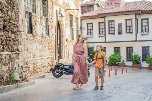 Mom and son tourists in Old town Kaleici in Antalya. Turkiye. Panoramic view of Antalya Old Town port, Taurus mountains and Mediterrranean Sea, Turkey. Traveling with kids concept.