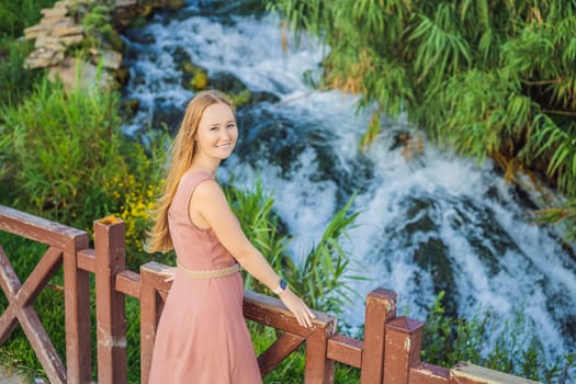 Beautiful woman with long hair on the background of Duden waterfall in Antalya. Famous places of Turkey. Lower Duden Falls drop off a rocky cliff falling from about 40 m into the Mediterranean Sea in amazing water clouds. Tourism and travel destination photo in Antalya, Turkey. Turkiye.