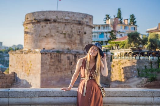 Woman tourist on background of Hidirlik Tower in Antalya against the backdrop of the Mediterranean bay of the ancient Kaleici district, Turkey. Turkiye.