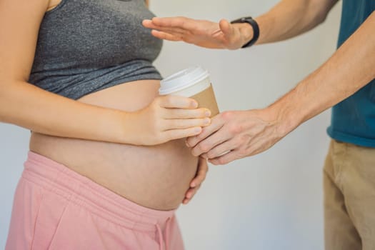 Husband forbids pregnant wife to drink coffee. A pregnant woman holds a cup of coffee in her hands. Caffeine safety, myths about coffee during pregnancy concept.