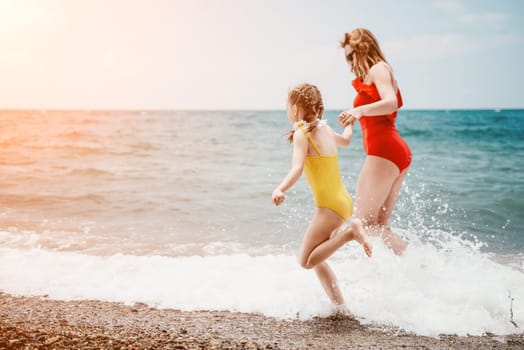 Happy loving family mother and daughter having fun together on the beach. Mum playing with her kid in holiday vacation next to the ocean - Family lifestyle and love concept.