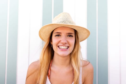 Headshot of young happy blond woman wearing summer hat looking at camera. Lifestyle concept.