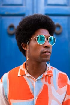 Vertical portrait of young confident and cool black man wearing sunglasses outdoors. Lifestyle concept.