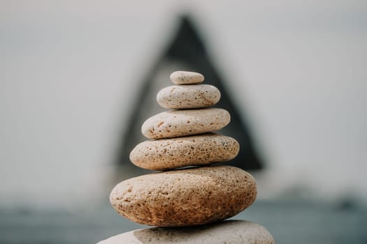 Pyramid stones on the seashore with warm sunset on the sea background. Happy holidays. Pebble beach, calm sea, travel destination. Concept of happy vacation on the sea, meditation, spa, calmness.