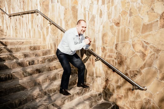 Portrait of a senior professional man in a suit with various problems. A middle-aged businessman with a briefcase descends the stairs.