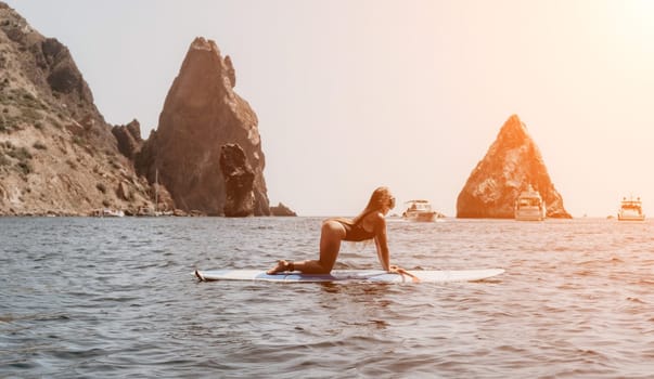 Close up shot of beautiful young caucasian woman with black hair and freckles looking at camera and smiling. Cute woman portrait in a pink bikini posing on a volcanic rock high above the sea