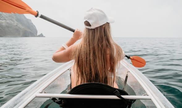 Woman in kayak back view. Happy young woman with long hair floating in transparent kayak on the crystal clear sea. Summer holiday vacation and cheerful female people having fun on the boat.