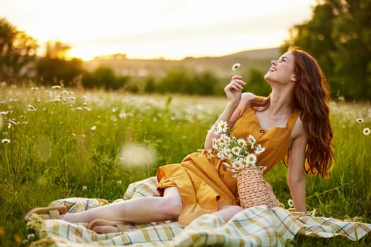 beautiful woman, in a summer orange dress enjoys nature while sitting in a chamomile field. High quality photo