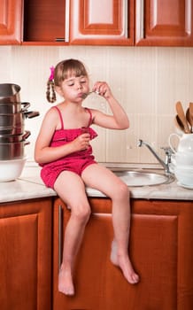 girl washes dishes and blows soap bubbles in the kitchen