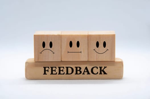 Sad, neutral and happy emotion faces on wooden cubes with white background cover. Customer feedback and evaluation concept