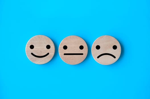 Happy, neutral, and sad emotion faces on wooden circle. Customer satisfaction and evaluation concept.