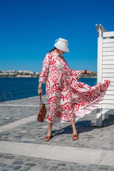 woman in a hat and dress enjoys the blue sea and summer. Welcome summer