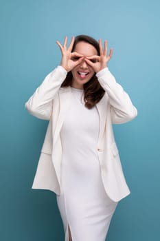 European pretty brunette young woman in a dress and jacket with a grimace.