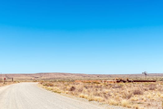 A road scene, with a stone livestock enclosure and windmill, at Putsonderwater. in the Northern Cape Province