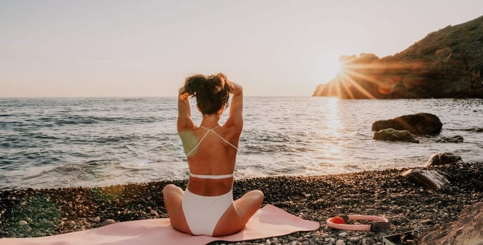 Young woman in swimsuit with long hair practicing stretching outdoors on yoga mat by the sea on a sunny day. Women's yoga fitness pilates routine. Healthy lifestyle, harmony and meditation concept.