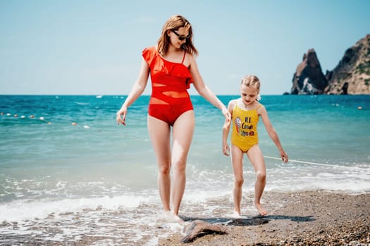 Happy loving family mother and daughter having fun together on the beach. Mum playing with her kid in holiday vacation next to the ocean - Family lifestyle and love concept.