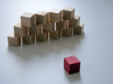 Wall of wooden cubes and in front of it is red. Overcoming difficulties and obstacles.