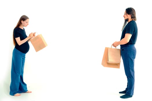 Portrait happy young pregnant woman and her husband with shopping bags and touching her big belly isolated on white background. Pregnancy shopping concept happy young family with shopping bags