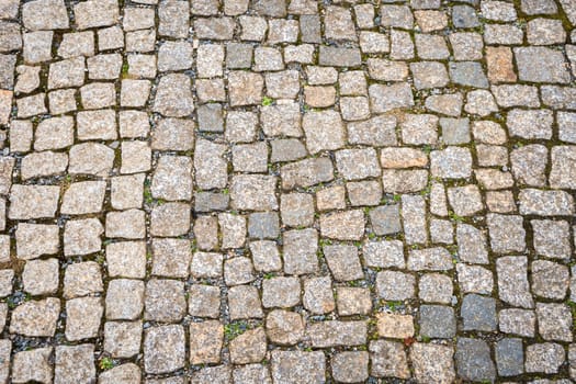 The road is paved with decorative stone. The old road of granite paving stones.