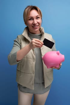 young blond hair woman keeps savings in a piggy bank and on a credit card.