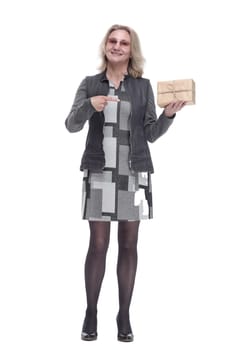 in full growth. happy young woman pointing at the gift box. isolated on a white background